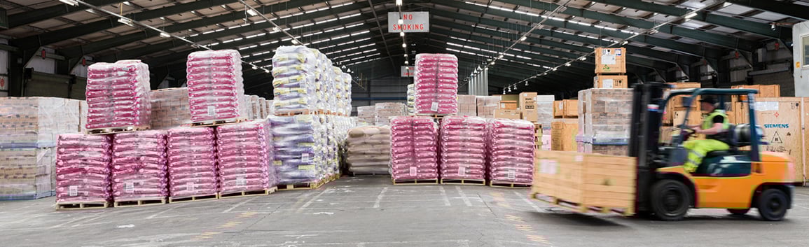 inside-port-warehouse-forklift-driving-past-pallets-of-cargo